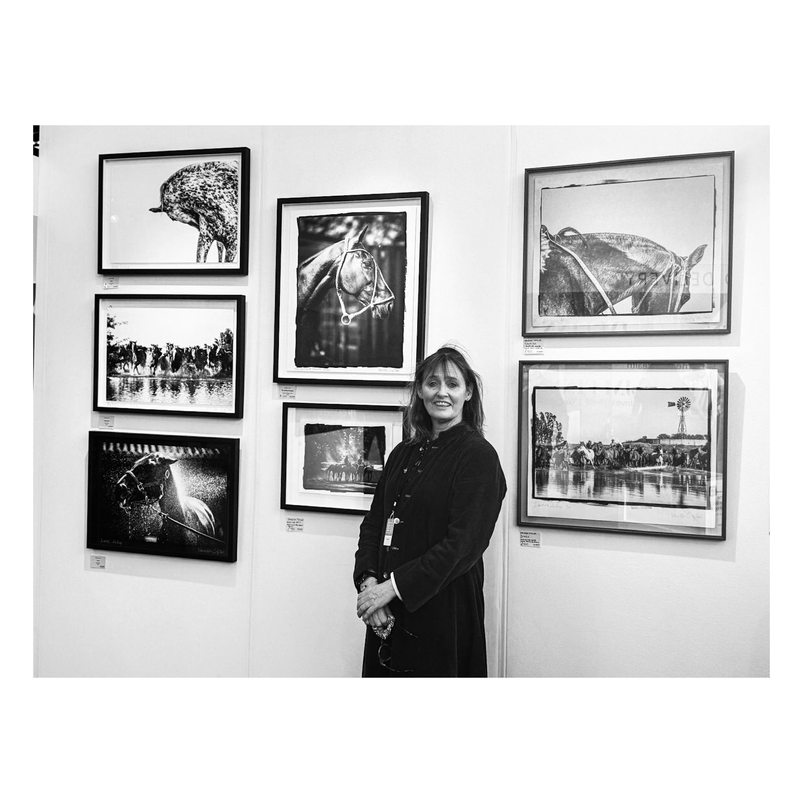 Vanessa Taylor beside a wall of her framed equine prints at an art fair